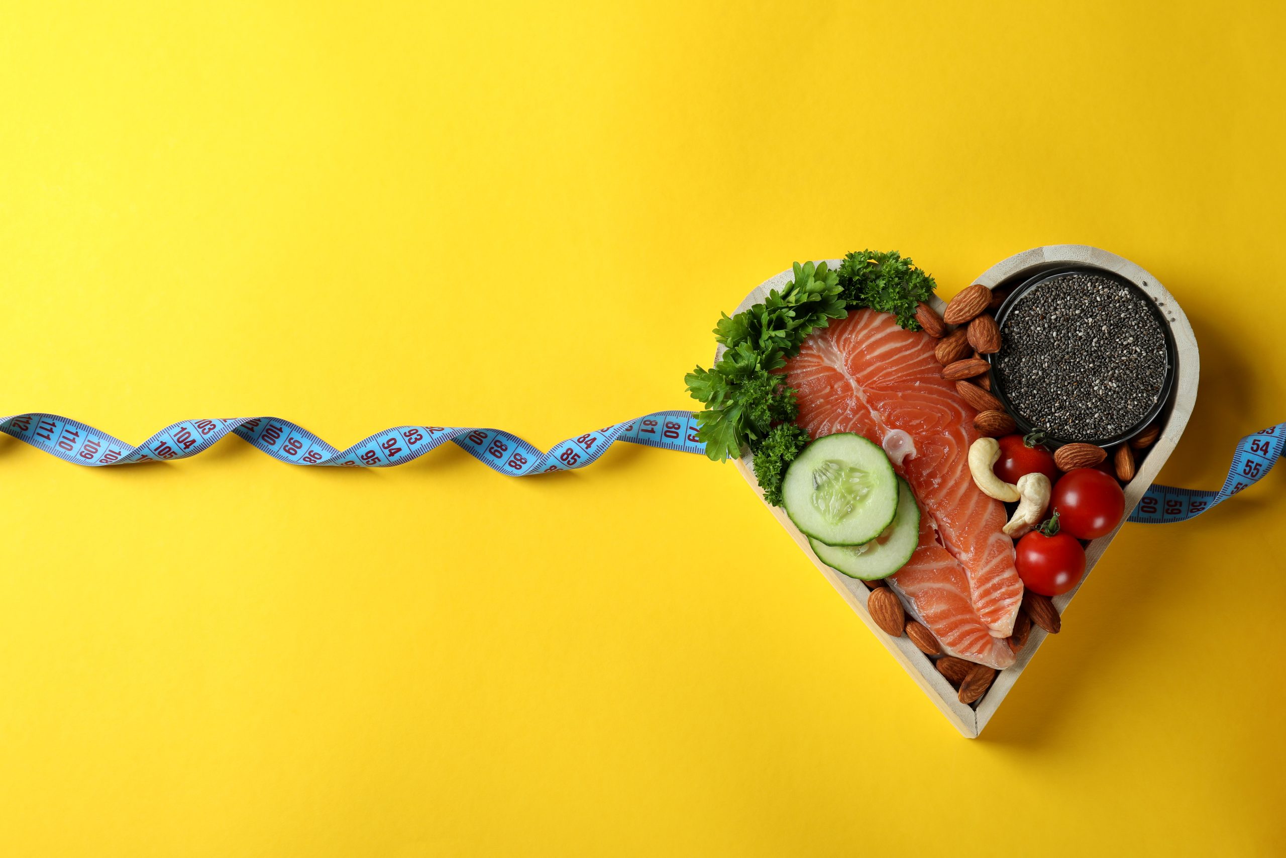 Healthy food in heart and measuring tape on yellow background